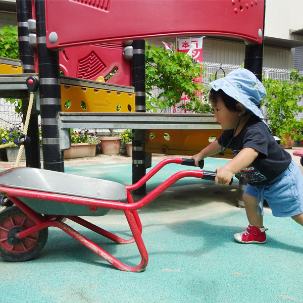 園庭で手押し車を押す園児