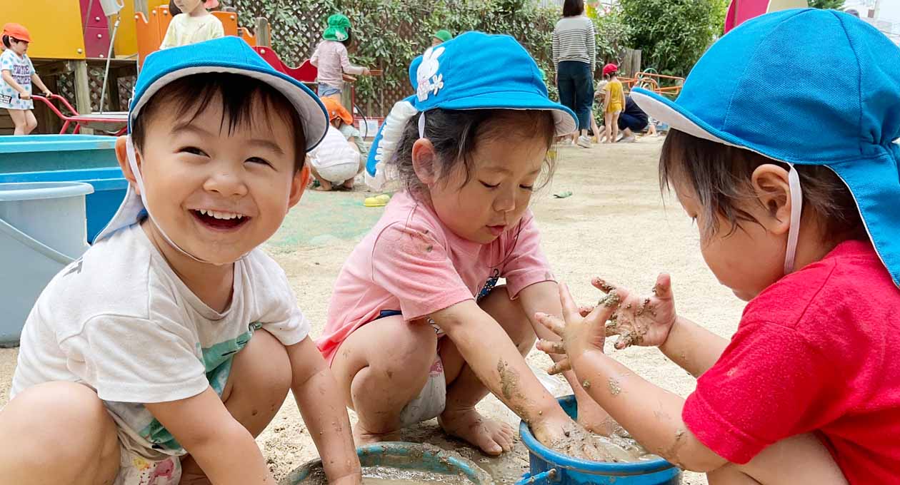 園庭で泥遊びする園児たち