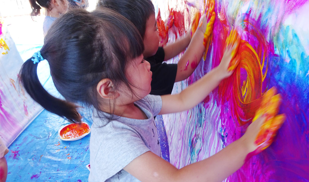 絵の具を使って手で絵を描く園児たち